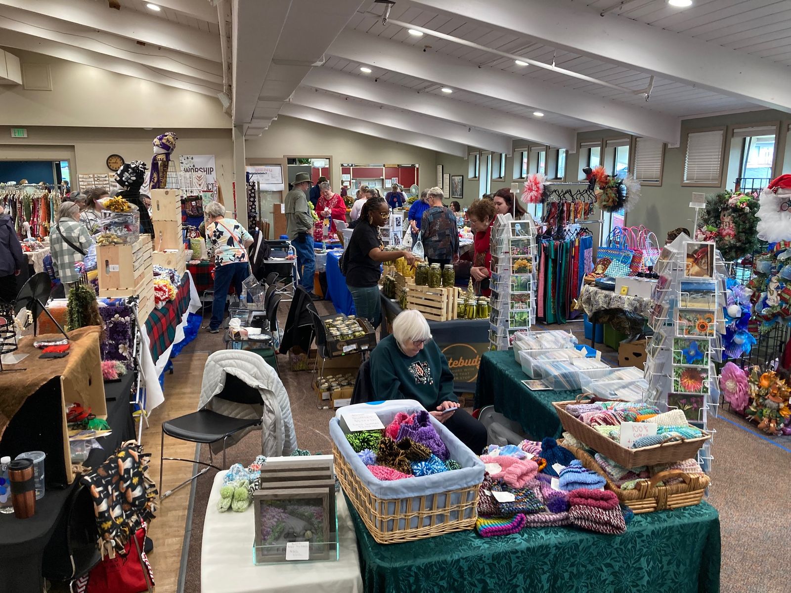 Baskets of hand-knit hats, photo cards, and jars of homemade pickles on vendor tables