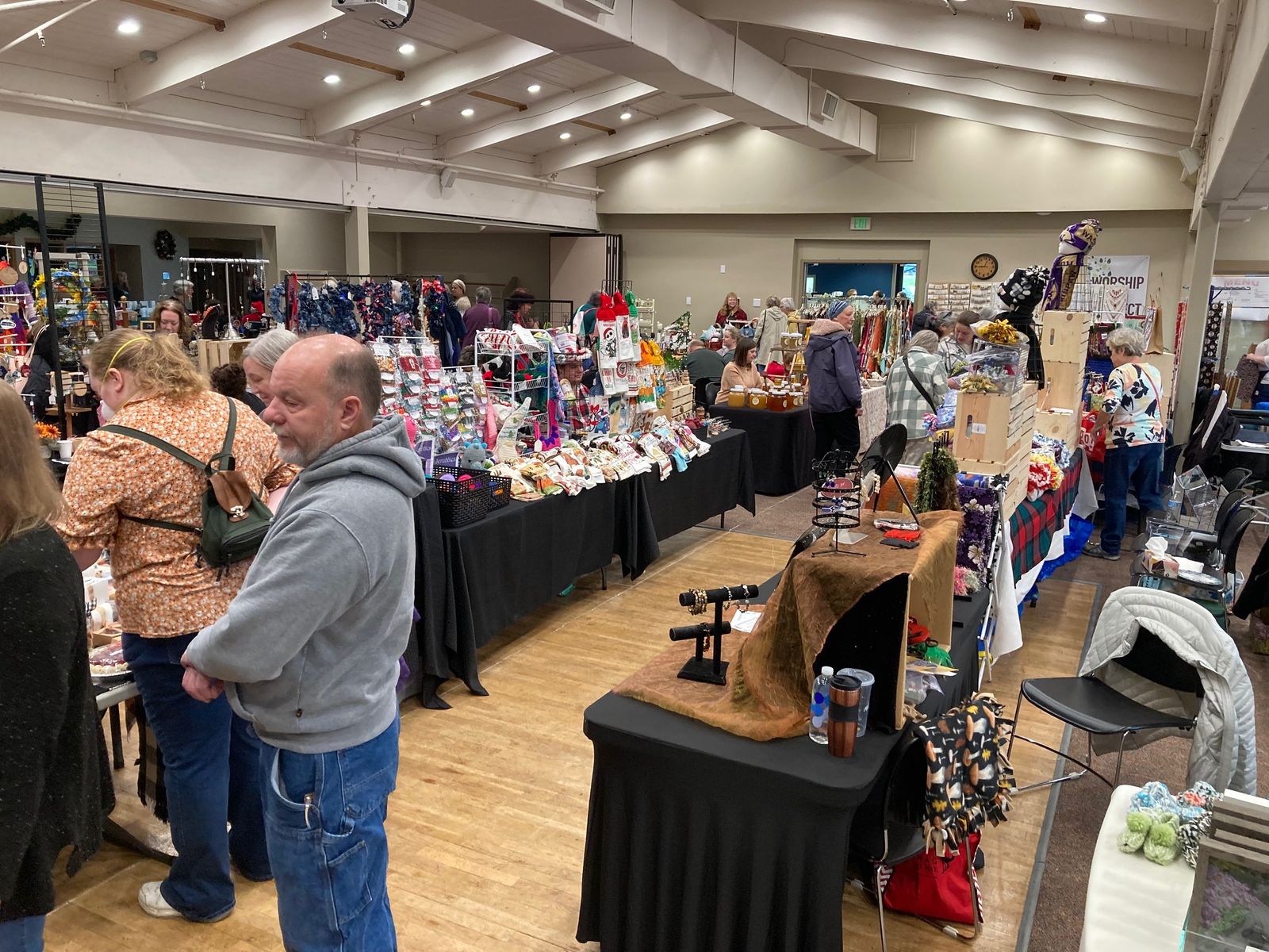 Long tables of handmade towels, ornaments, and crafts with shoppers in the aisles